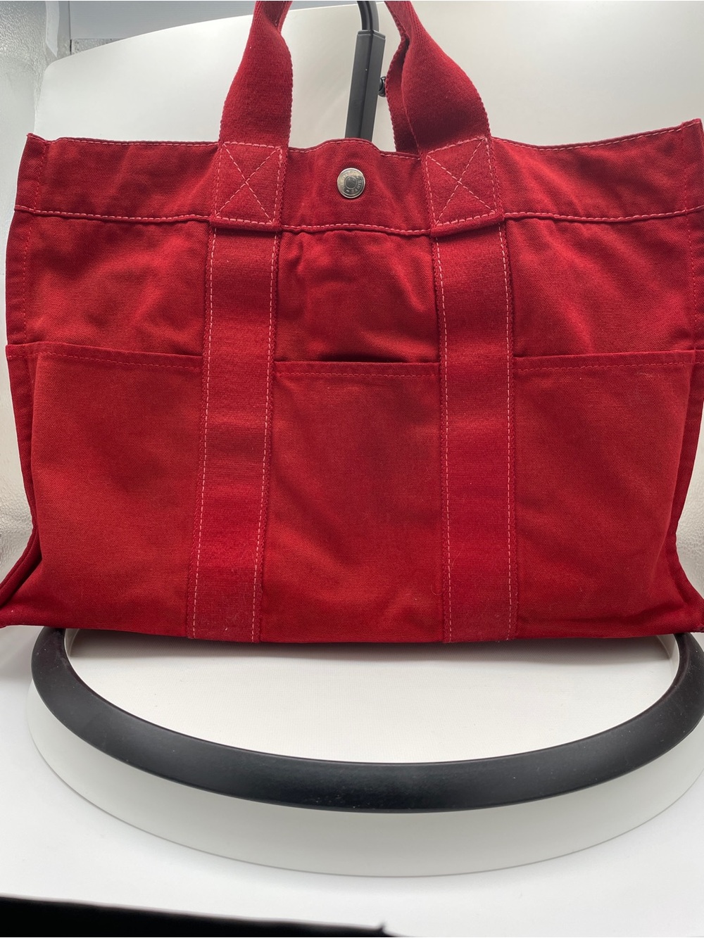 Herme’s Fourre Tout MM red canvas tote features dual handles a snap closure